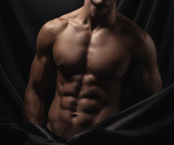 Torso masculino definido bajo una iluminación tenue, frente a un drapeado de seda oscura, representación visual del bienestar masculino premium.